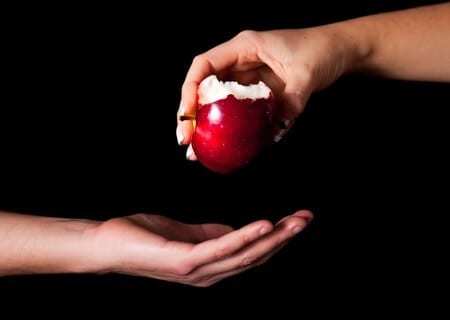 Frau gibt einen Mann einen Apfel