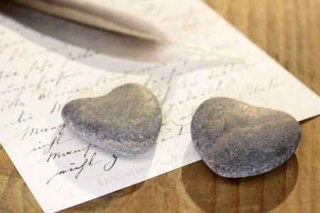 Zwei steinerne Herzen mit Feder und alten Brief