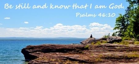 man on cliff overlooking lake superior with quote, be still and know that i am god