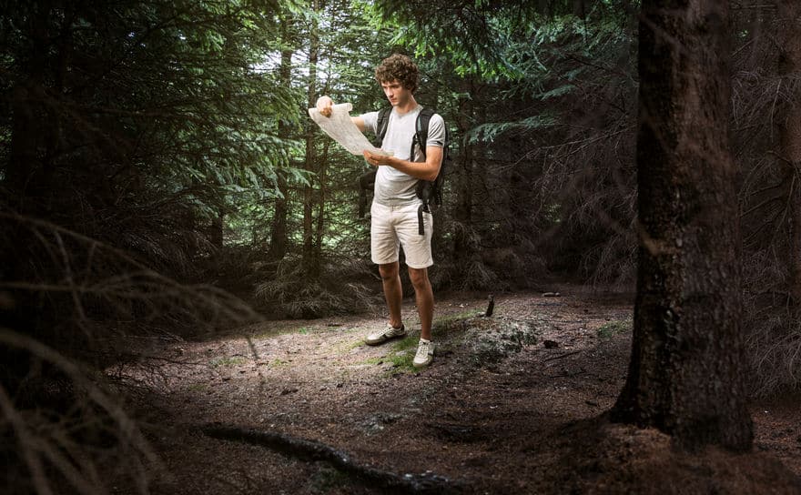 Junge männliche Blick auf Karte und Planungsreise oder in den dunklen Wäldern verloren gehen